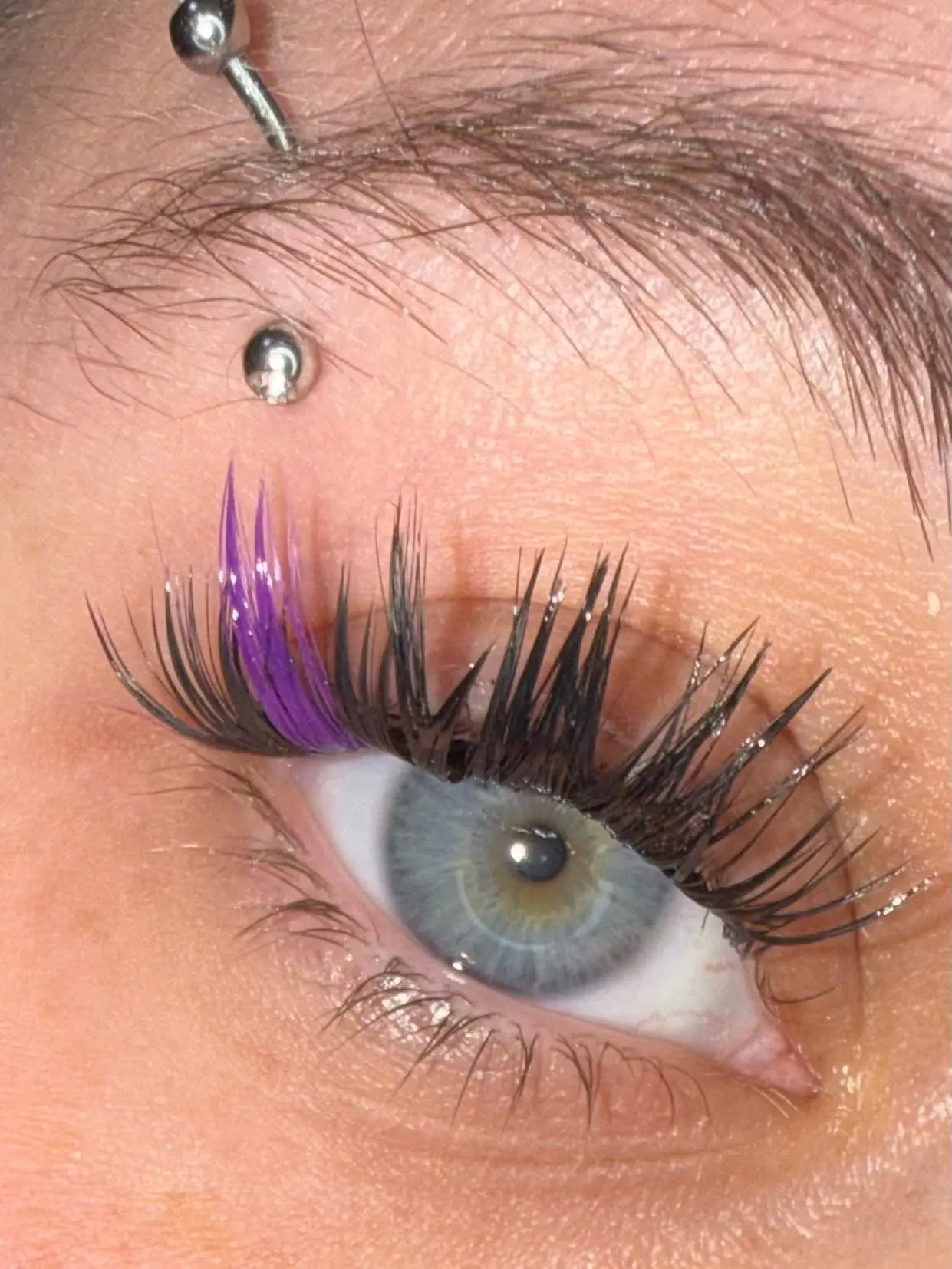 Dramatic cluster lashes with purple color accent and eyebrow piercing