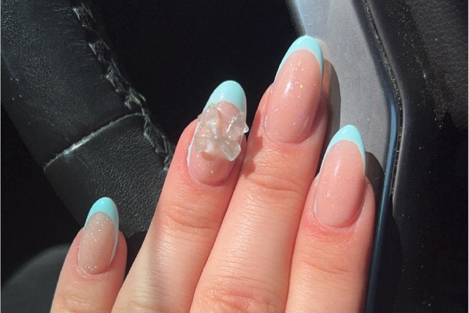 Blue French tip gel nails with sparkle and 3D bow accent